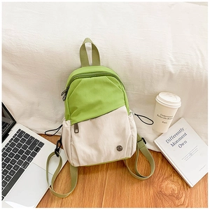 Close-up of stylish green and beige backpack with side drawstring pockets in a modern setting