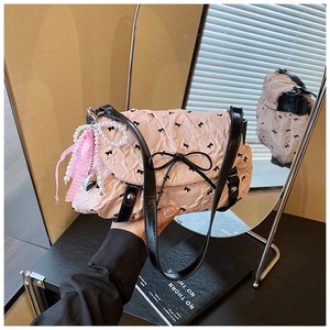 Close-up of pink quilted crossbody bag with black bows and pearl heart charms
