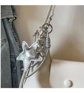 Gros plan sur les charms étoile argentée et chien ballon d'un sac à main beige