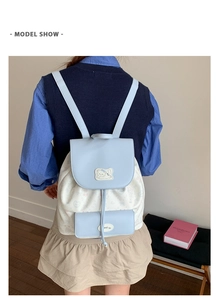 Détail du sac à dos contrasté bleu et blanc avec patch de chat brodé et fermeture à cordon