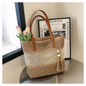 Detail der handgeflochtenen Strohtasche mit dreifarbigen Streifen und Quastenanhänger