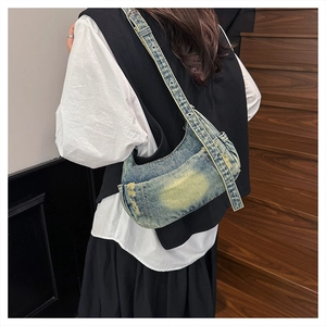 Detail of washed denim shoulder bag showing vintage distressed edges and metal eyelets