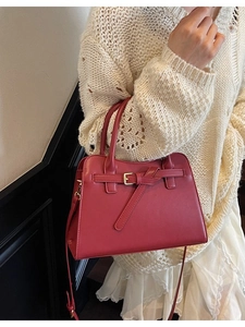 Elegant red leather wedding handbag with gold buckle, worn with a white dress