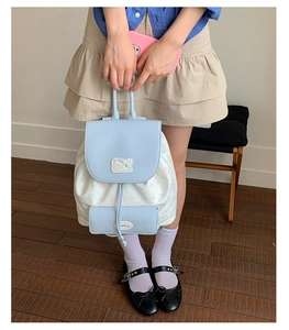 Detail of light blue floral backpack featuring a cute cat patch and drawstring closure