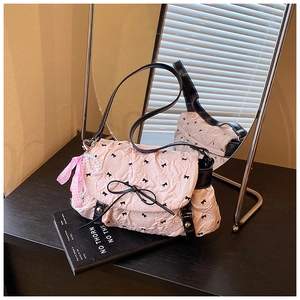 Detail of pink quilted puff bag with black bows, pearl charms and leather strap