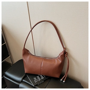 Detail of caramel hobo bag featuring smooth leather texture and side knot silver bead charm