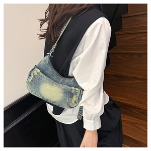 Close-up of vintage distressed denim crossbody bag with fringe details and washed finish