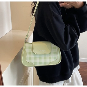 Détail d'un sac à bandoulière damier vert clair avec rabat en cuir sur une tenue