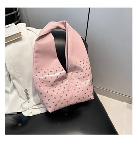 Close-up of pink glossy patent leather punk bag with shiny silver metal rivet studs