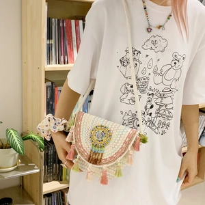Detail view of woven shoulder bag with geometric embroidery, beads and colorful tassels