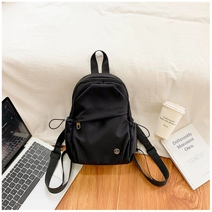 Detail view of black waterproof nylon backpack with adjustable straps and metal M logo