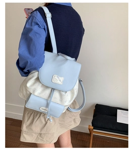 Detail view of a light blue contrast floral backpack with a cute cat patch and drawstrings