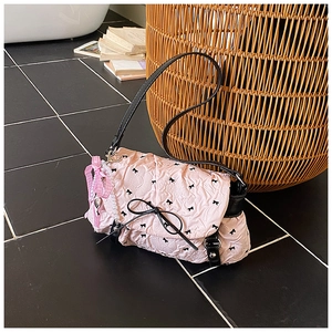 Detail of pink quilted puff bag with black bow prints and elegant pearl chain accent