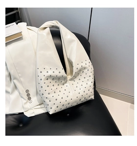 Detailed close-up of ivory punk shoulder bag with silver studs and knotted strap