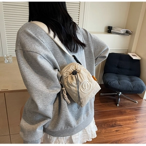 Detail of beige nylon drawstring crossbody bag featuring a white embroidered logo