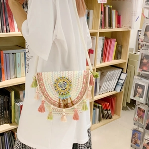 Close-up of ethnic woven bucket bag with rainbow tassels and colorful beaded disk