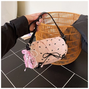 Detailed shot of pink pleated bag with black bow patterns and pearl heart charms