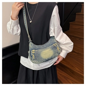 Detail of vintage washed denim hobo bag showing distressed texture and utility pocket