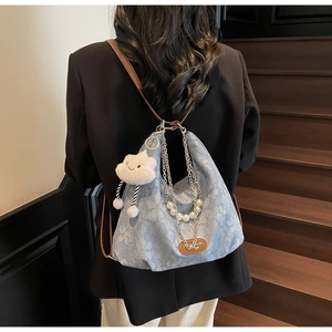 Detail of floral denim crossbody bag with silver chains, pearls and cloud plush charm