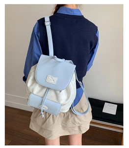 Détail d'un mini sac à dos bleu clair et crème avec écusson chat mignon et lanières