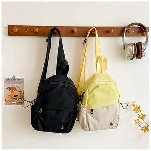 Détail de mini sacs à dos en nylon noir et jaune-blanc suspendus sur un portant