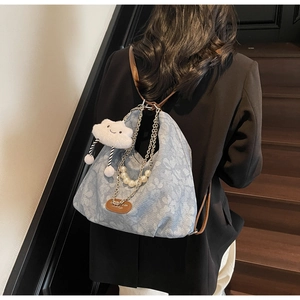 Floral blue denim bag detail with brown leather strap and decorative metal chain