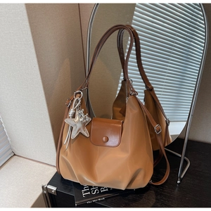 Sac fourre-tout caramel avec charme étoile argentée posé sur une table en bois