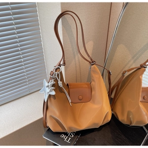 Détail d'un sac à bandoulière marron avec rabat en cuir et accessoire pendentif étoile