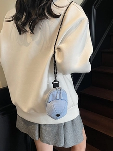 Mini light blue hat-shaped crossbody bag with checkered fabric on a female model
