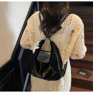 Détail du sac à dos en cuir verni noir brillant avec pendentif étoile sur modèle