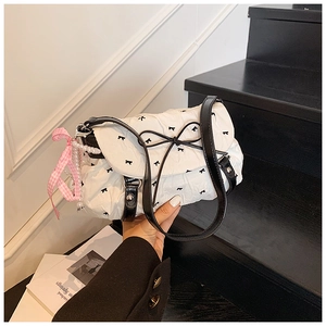 Close-up of white cloud bag featuring black bow prints and a pink pearl charm