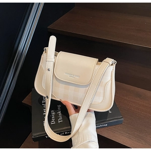 Détail du sac bandoulière beige avec texture en damier et logo imprimé sur le rabat