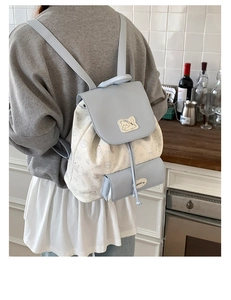 Detail view of stylish light blue backpack with cartoon print and mini pendant on a model
