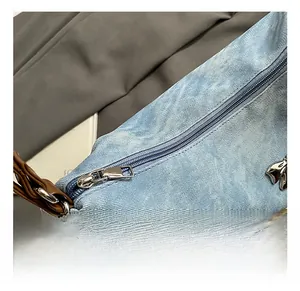 Detailed shot of denim fabric bag with pearl chain strap and silver bow pendant