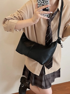 Minimalist black crescent shoulder bag with metallic ball detail and knotted leather strap