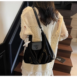 Détail d'un sac cabas noir brillant avec charm étoile sur un escalier en bois
