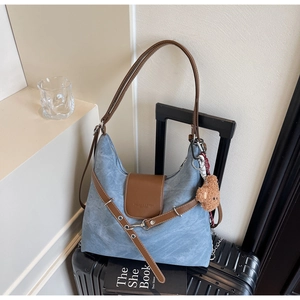 Detail der blauen Denim-Tasche mit braunem Lederbesatz, Plüschbär-Anhänger und Seidentuch