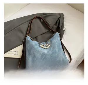 Detail of light blue denim tote with pearl bow chain and brown faux leather handle