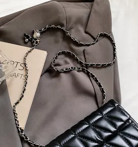 Detail of black quilted leather bag with silver metal ball and woven chain strap