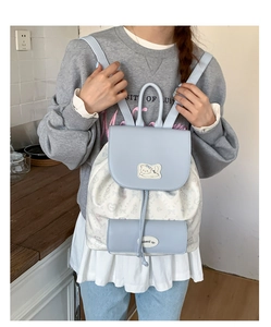 Detailed view of light blue and white cartoon backpack with cat patch on a female model