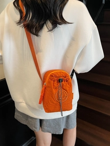 Mini orange nylon drawstring crossbody bag with embossed logo and adjustable strap