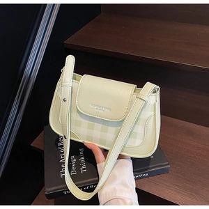 Détail d'un sac porté épaule en cuir à damier vert clair avec une large bandoulière