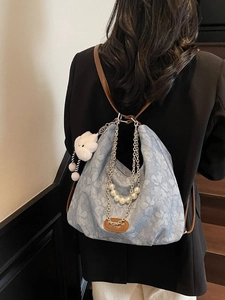 Blue floral canvas hobo bag with pearl chain and cloud charm shown on model