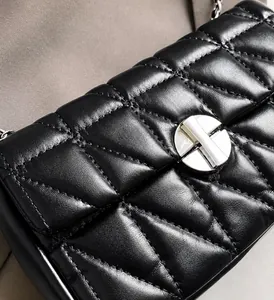 Detail of black quilted leather bag featuring a polished silver round twist lock buckle