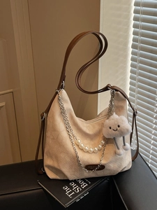 Off-white corduroy tote bag with pearl chain and leather straps in a home setting