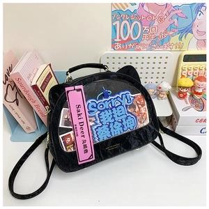 Detail of black cat-ear ita bag with heart-shaped window and pink branded tag