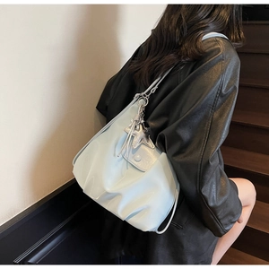 Détail d'un sac cabas plissé bleu clair avec pendentif étoile porté sur une veste en cuir