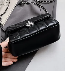 Close-up of black quilted shoulder bag with silver chain strap and metal swivel lock