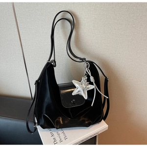 Détail du sac cabas noir avec pendentif étoile et rabat en cuir brillant de luxe