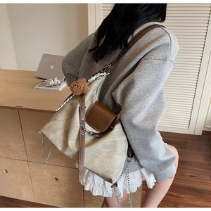 Detail der beigen Segeltuchtasche mit braunem Lederbesatz, Kette und Bärenanhänger